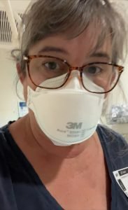 middle aged white woman with dark hair and glasses, she is wearing an N-95 mask
